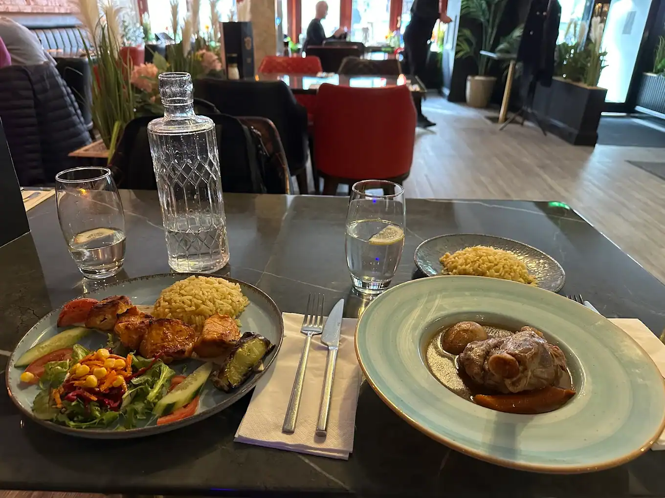 Delicious meal featuring grilled chicken, vegetables, and hearty stew at a stylish restaurant.