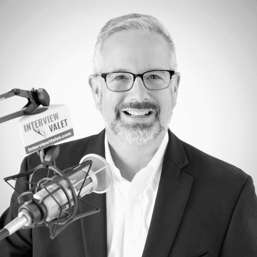 Dominic Monkhouse, business coach in London, smiles with microphone.