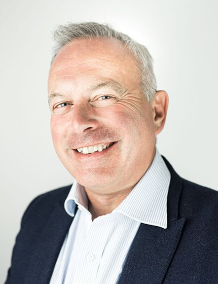 Professional portrait of a smiling middle-aged man in business attire.