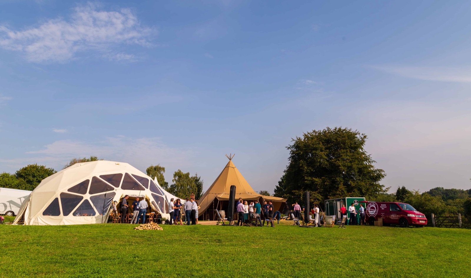 Entrepreneur coaching outdoor event with tents and attendees in a green field.