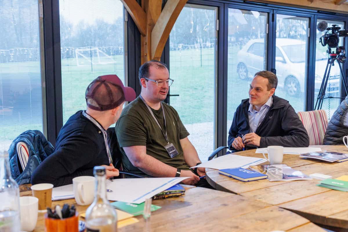 Founder CEOs in a group coaching discussion around a wooden table