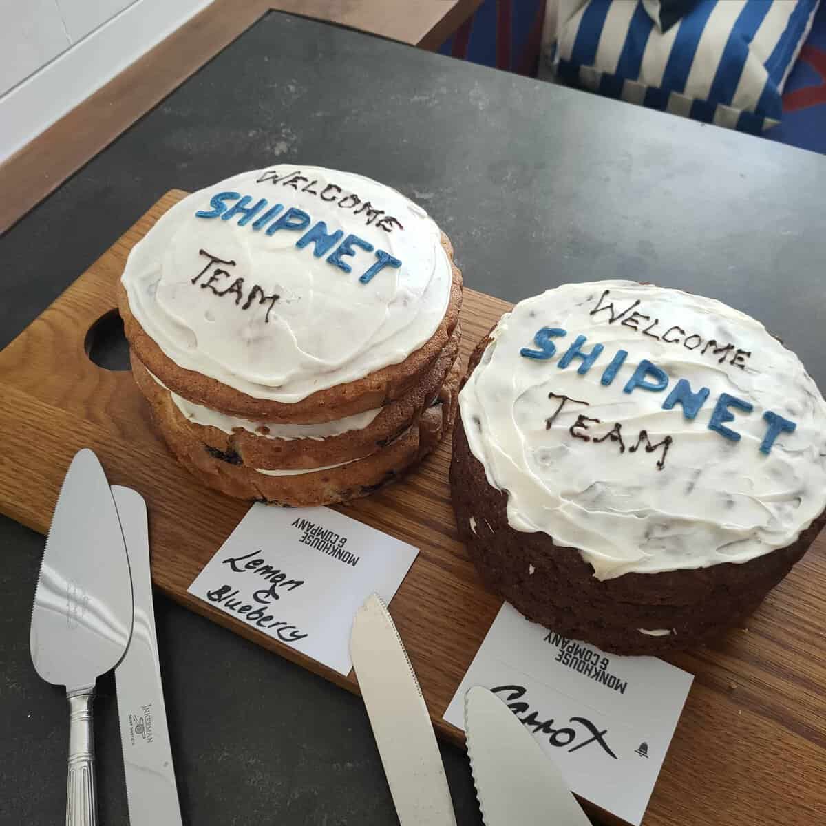 Two decorated celebration cakes with "Welcome Shipnet Team" message on top.