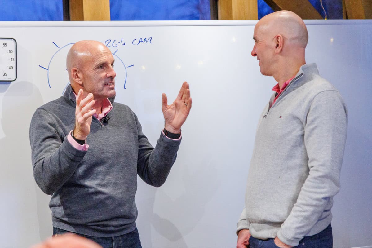 Dominic Monkhouse in animated one-to-one pricing coaching conversation with a founder at a whiteboard