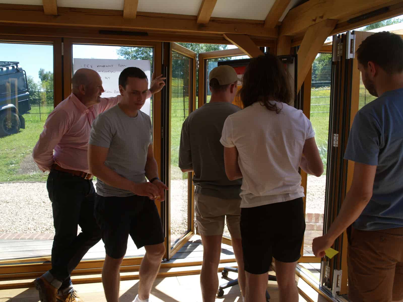 Leadership team gathered around a whiteboard during a daily huddle workshop in a farm barn setting