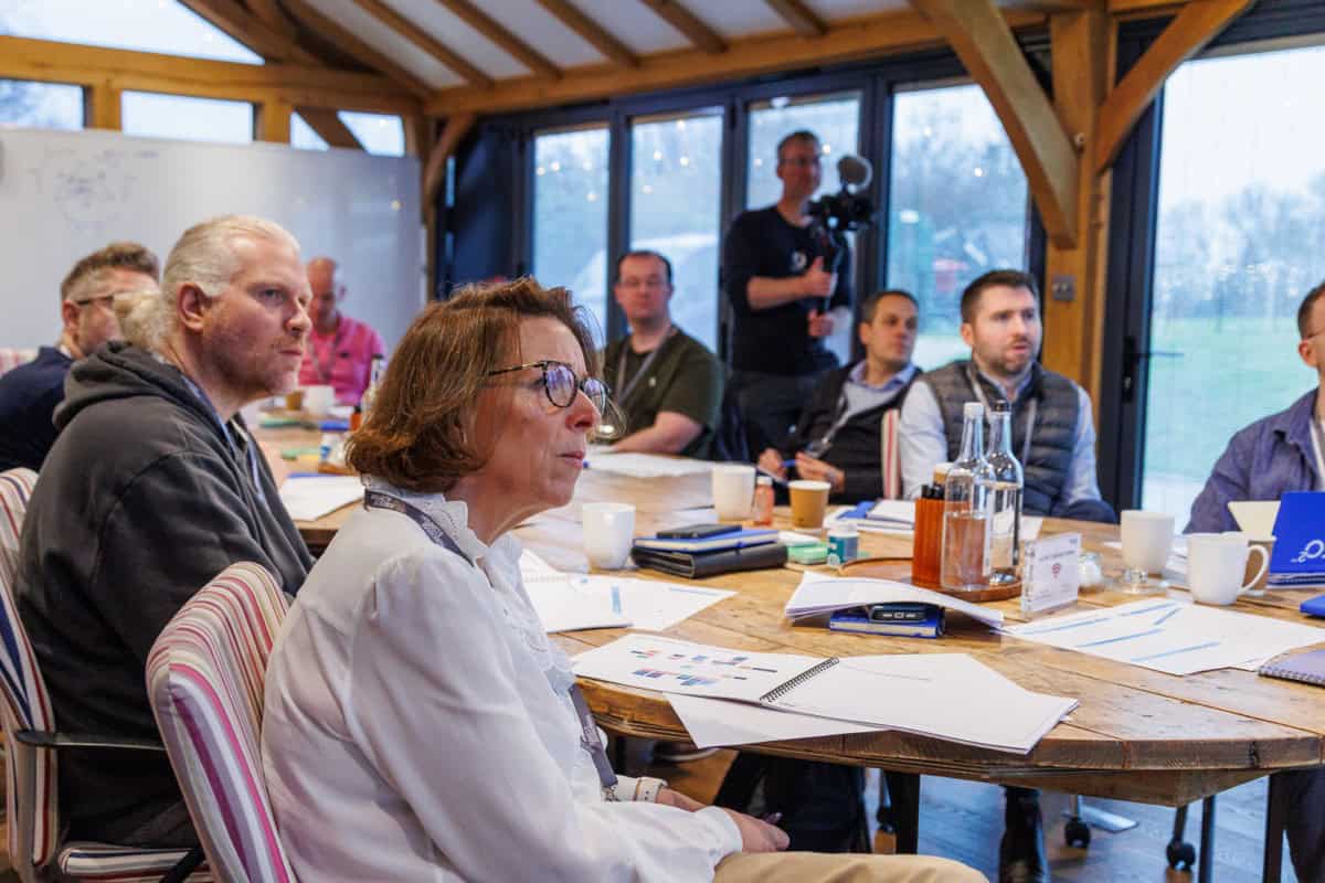 A leadership team discusses their plan on a page around a wooden table during a strategy workshop