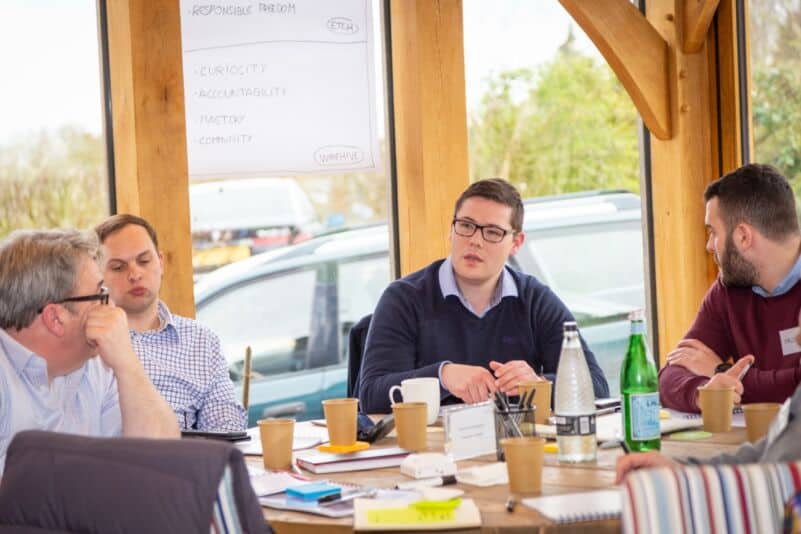 Business meeting with diverse professionals discussing strategies at a wooden table.